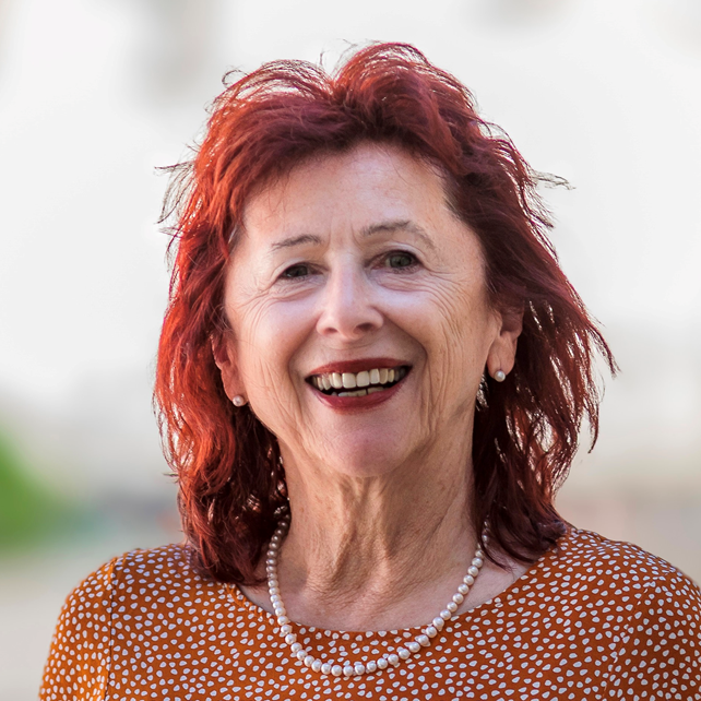 Auf dem Foto ist die Quartiersmanagerin mit roten Haaren und einer roten Bluse mit weißen Pünktchen abgebildet.
