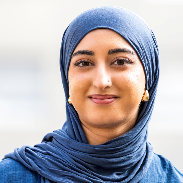 Auf dem Foto ist eine studentische Mitarbeiterin mit einem blauen Tuch über den Haaren und blaue Bluse abgebildet.
